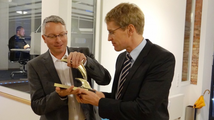 Daniel Günther, MdL, mit Arne Rüstemeier und dem goldenen Delphin aus Cannes bei bewegtbild in Flensburg